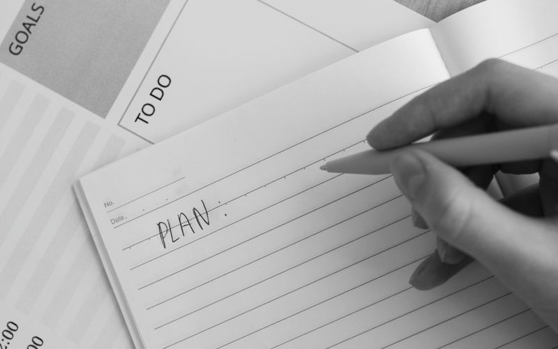 A hand writing a plan in a notebook.