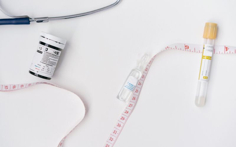 Small glass vials and a syringe arranged on a white surface.