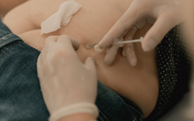 A close-up of a subcutaneous injection into the abdomen.