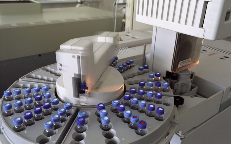Rows of sealed glass vials in laboratory analysis equipment.