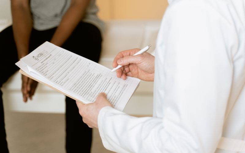 A clinician reviewing a medical form during a consultation.